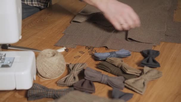 Plier le tissu de laine à carreaux marron. Jeune homme travaillant comme tailleur et utilisant une machine à coudre en atelier . — Video