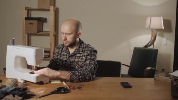 Good looking young man working as a tailor and using a sewing machine in a textile studio. makes bow ties — Stock Video