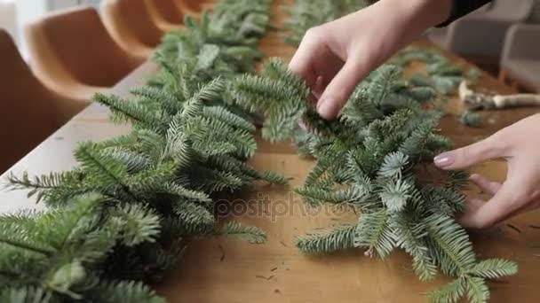 Florista no trabalho: mãos de mulher que fazem decorações de Natal grinalda de abeto Nobilis. Feliz ano novo jantar festa — Vídeo de Stock