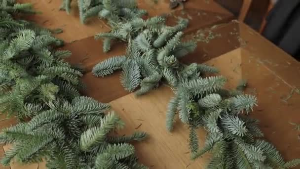 Florista no trabalho: mãos de mulher que fazem decorações de Natal grinalda de abeto Nobilis. Feliz ano novo jantar festa — Vídeo de Stock