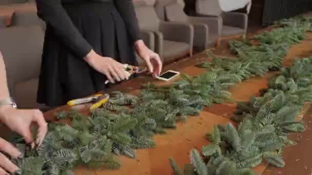 Bloemist op het werk: vrouw handen maken Kerst decoraties garland van Spar Nobilis. Gelukkig Nieuwjaar diner feest — Stockvideo