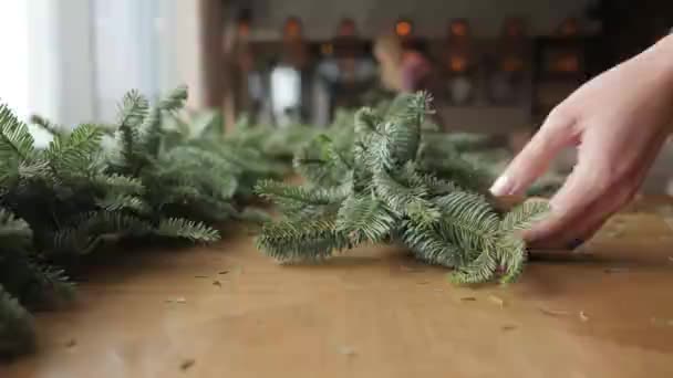 Primer plano de la mano. Florista en el trabajo: manos de mujer haciendo adornos navideños guirnalda de abeto Nobilis. Feliz año nuevo cena fiesta — Vídeos de Stock