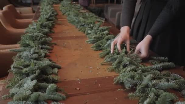 Флорист за работой: женщина руками делает рождественские украшения гирлянды из ели Nobilis. С наступающим Новым годом! — стоковое видео