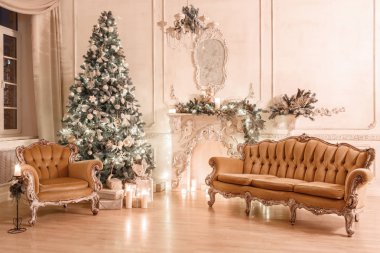 Noel akşam mum ışığında. Klasik dairelerde beyaz bir şömine, dekore edilmiş ağaç, kanepe, büyük pencereler ve avize.