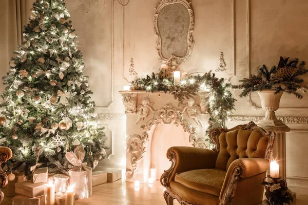 Christmas evening by candlelight. classic apartments with a white fireplace, decorated tree, sofa, large windows and chandelier. — Stock Photo, Image