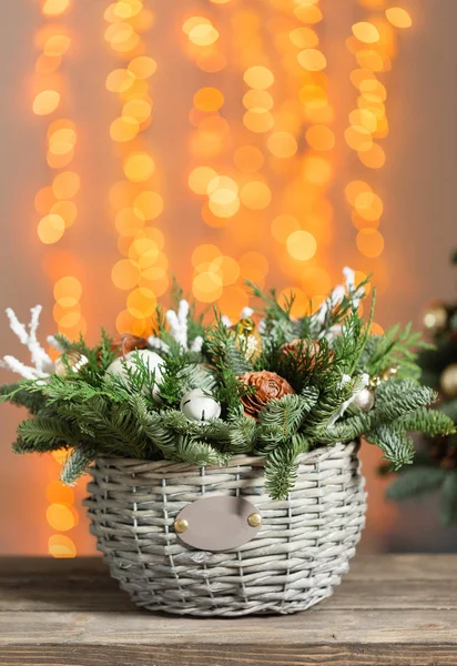 Bela composição de Natal em uma cesta de vime em tábuas de madeira. Preparação para o conceito de férias. Flower shop é um trabalho principal de um florista profissional. espaço de cópia. luzes guirlanda — Fotografia de Stock