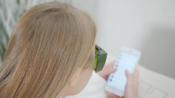 Porträt eines Mädchens mit Brille, benutzt ein Telefon. Laserepilation und Kosmetologie. Haarentfernung an Damenbeinen. im kosmetischen Beauty Clinic Spa. — Stockvideo