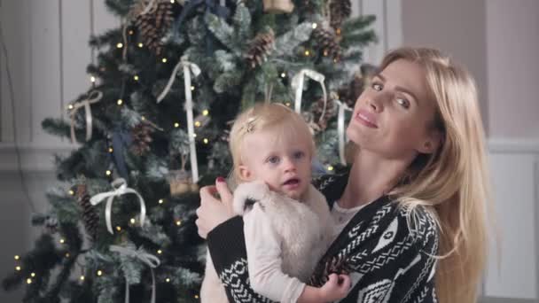 Feliz madre e hija abrazando. Chimenea blanca y árbol decorado sobre fondo. Celebración de Navidad o Año Nuevo . — Vídeos de Stock