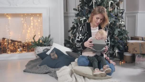 Feliz madre e hija abrazando. Chimenea blanca y árbol decorado sobre fondo. Celebración de Navidad o Año Nuevo . — Vídeos de Stock