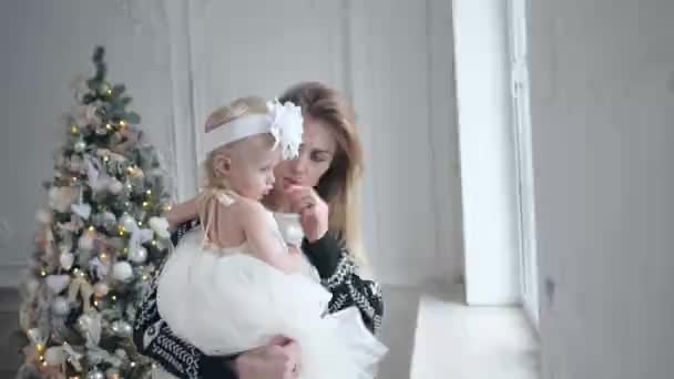 Happy mother and daughter embracing. White wall and decorated tree on background. Christmas or New year celebration. — Stock Video