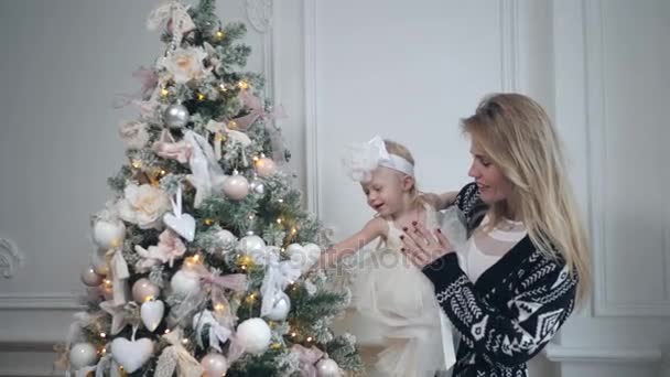 Lycklig mor och dotter omfamna. Vit vägg och dekorerade träd på bakgrunden. Jul eller nyår celebration. — Stockvideo