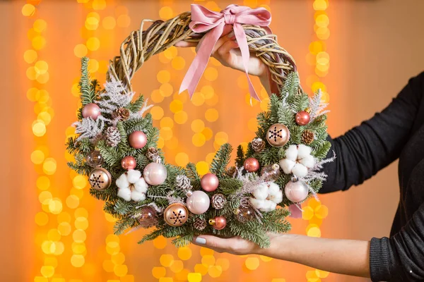 Güzel Noel çelenk kadın elinde. Tatil kavramı için hazırlık. Çiçekçi dükkanı profesyonel çiçekçi ana bir eseridir. arka planda parlak garland — Stok fotoğraf
