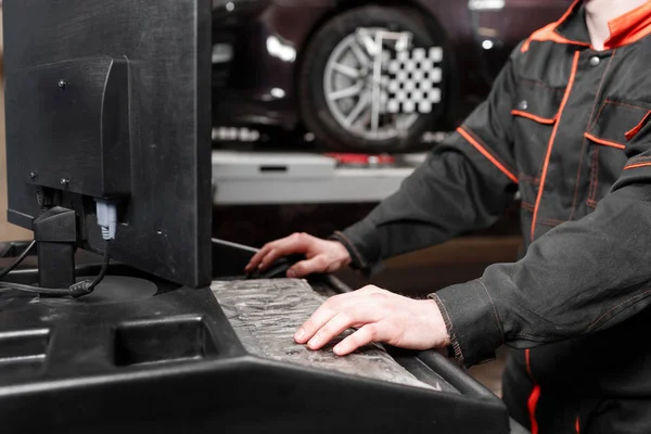 auto mechanic performs diagnostics and configuration on the computer . Wheel alignment equipment on a car wheel in a repair station