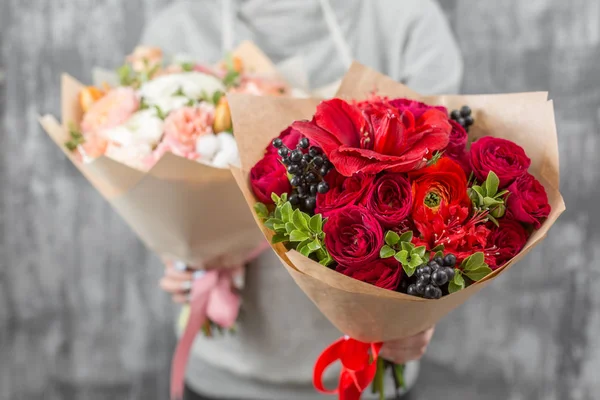 Dois belos buquês de luxo de flores mistas na mão da mulher. o trabalho da florista em uma loja de flores. cor vermelha brilhante e delicada — Fotografia de Stock