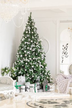 Noel sabahı. Beyaz şömineli klasik daireler, dekore edilmiş ağaç, parlak kanepe, büyük pencereler.