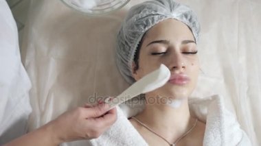 Spatula köpük yüzünden kaldırın. Genç güzel kadın güzellik salonları içinde tedavi alma. Yüz temizleyici köpük kullanarak.