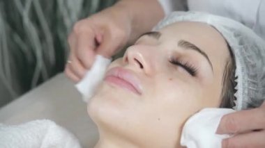 Steril peçete yüzüyle sil. Genç ve güzel bir kadın güzellik salonlarında tedavi görüyor. Yüz temizleme köpüğü kullan.