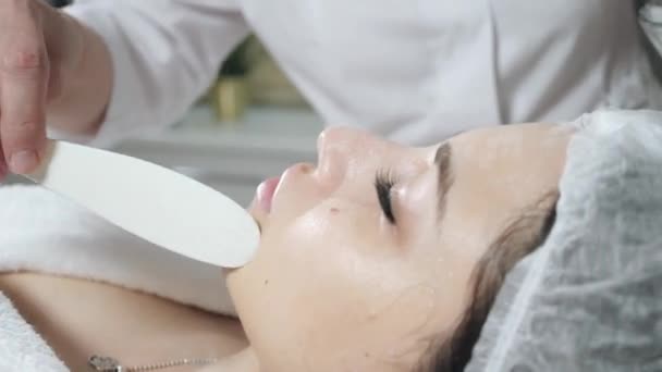 Retire com espuma de espátula do rosto. Jovem mulher bonita recebendo tratamentos em salões de beleza. Espuma de limpeza facial usando . — Vídeo de Stock