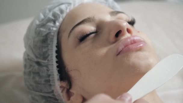 Retirer avec de la mousse de spatule du visage. Jeune jolie femme recevant des soins dans les salons de beauté. Mousse nettoyante pour le visage en utilisant . — Video
