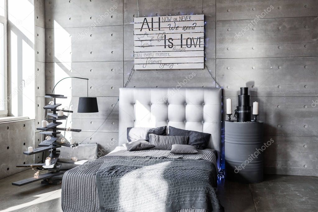 Modern empty bedroom in loft style with grey colors and wooden hand made Christmas tree with presents.