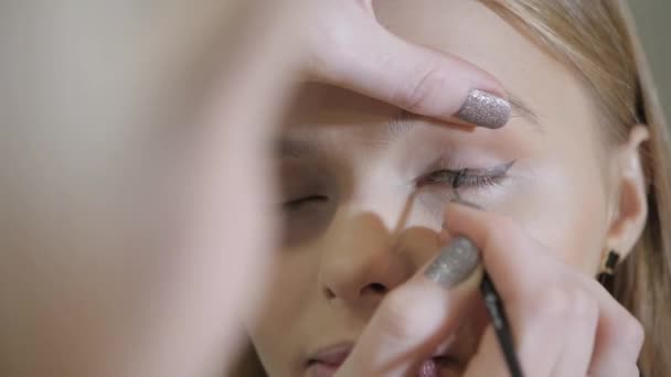 Olhos de tinta. Maquiagem artista criando maquiagem bonita para o modelo de loiras. Conceito de centro de beleza e spa — Vídeo de Stock