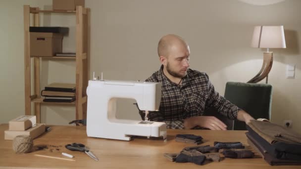 Le jeune homme sort une boîte de fils et d'aiguilles. Travailler comme tailleur et utiliser une machine à coudre dans un atelier textile. noeuds papillon en laine . — Video