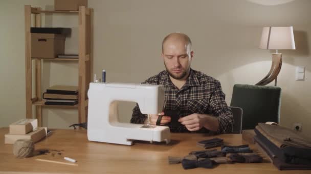 Fait des noeuds papillon. Jeune homme travaillant comme tailleur et utilisant une machine à coudre dans un atelier textile . — Video