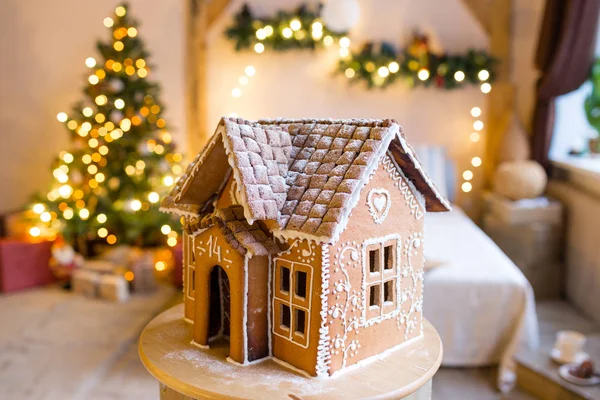gingerbread house over defocused lights of Chrismtas decorated fir tree