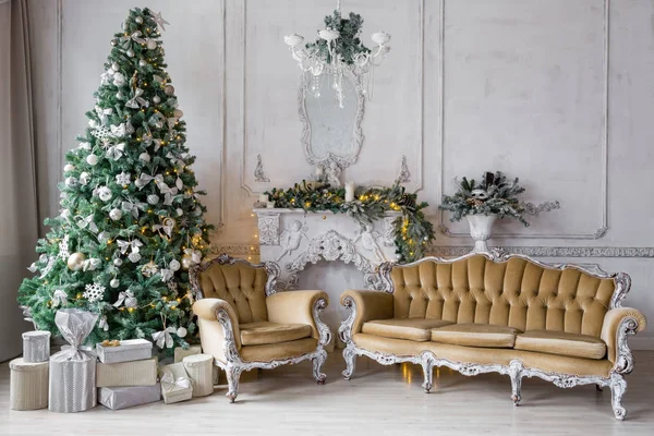 Mañana de Navidad. apartamentos clásicos con chimenea blanca, abeto decorado, sofá, grandes ventanales y lámpara de araña . — Foto de Stock