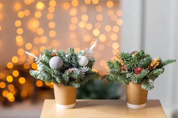 Две бумажные чашки для кофе на деревянном столе. Концепция рождественского кофе с украшениями елки. На заднем плане гирлянда из лампочки — стоковое фото