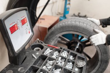 mükemmel denge tekerlek üzerinde sıfır. Teknisyen bir araba tekerleği döner. Aracın tamir - kurşun küçük ağırlık ve tekerlek Dengeleme için kerpeten. Araba Servisi.