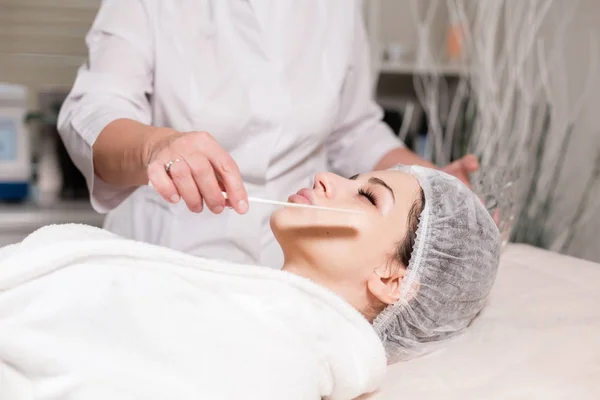 Verwijder met spatel schuim van het gezicht. Mooie jongedame ontvangen van behandelingen in schoonheidssalons. Facial zuivering met behulp van schuim. — Stockfoto