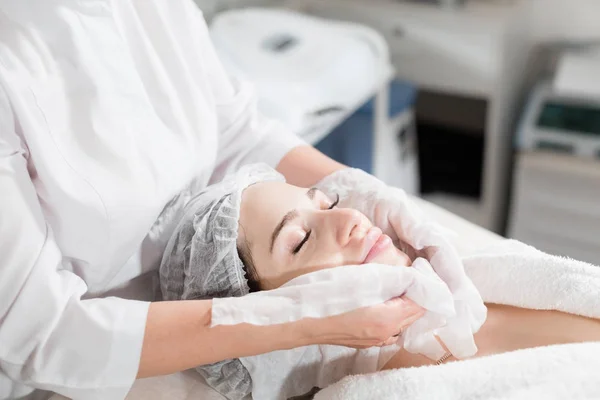 Limpe com o rosto de guardanapo estéril. Jovem mulher bonita recebendo tratamentos em salões de beleza. Espuma de limpeza facial usando . — Fotografia de Stock