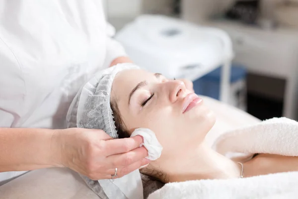 Limpe com o rosto de guardanapo estéril. Jovem mulher bonita recebendo tratamentos em salões de beleza. Espuma de limpeza facial usando . — Fotografia de Stock