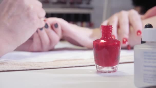 Manucure. Prendre un plongeon dans une bouteille de manucure au premier plan. Master applique un vernis dessin sur gel ongles dans le spa. Soin des ongles à bout portant par un spécialiste en salon de beauté . — Video