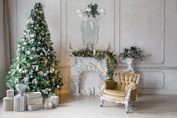 Mañana de Navidad. apartamentos clásicos con chimenea blanca, abeto decorado, sofá, grandes ventanales y lámpara de araña . — Foto de Stock