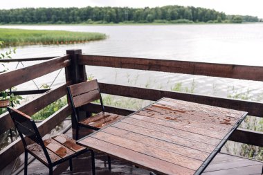 Orman büyük ahşap teras ile Nehri yakınında yazlık. Evi su Gölü, güzel bir banka. Tatil ve tatil için ideal bir yer. Masa ve sandalyeler üzerinde yağmur damlaları