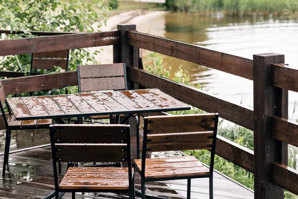 Antika ahşap masa ve sandalye için lake yakınındaki ahşap zemin üzerinde biraz ara. Büyük teraslı Nehri yakınında Ormanda Cottage.