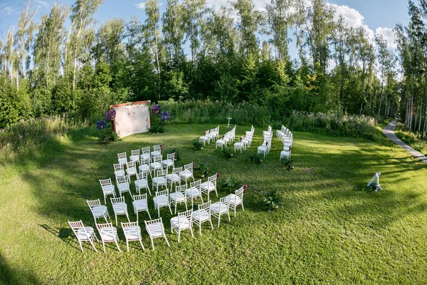 Güzel ayarı açık havada düğün gelin ve damat ve Konuklar için bekliyor. Çiçekleri ile süslenmiş beyaz sandalyeler vardır düğün bir ormandaki bölgesinde — Stok fotoğraf