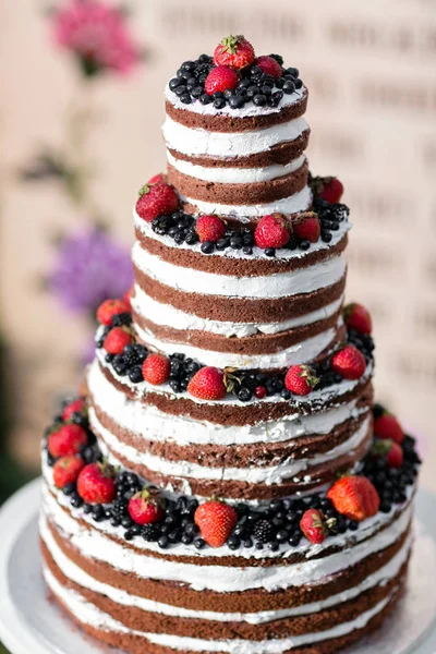 Bolo de casamento de várias camadas redondo com esponja, nata, engarrafamento e bagas em uma base circular. Mirtilos e morangos frescos — Fotografia de Stock