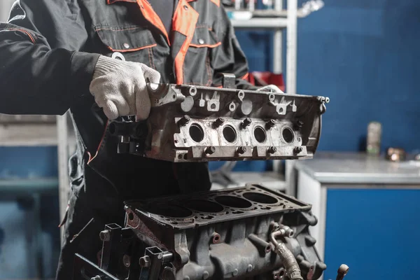 O mecânico desmonta o veículo do motor de bloco. Motor em um suporte de reparo com pistão e biela de tecnologia automotiva. Interior de uma oficina de reparação automóvel . — Fotografia de Stock