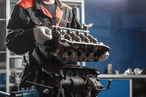 El mecánico desmonta el vehículo del motor del bloque. Motor en un soporte de reparación con pistón y varilla de conexión de la tecnología automotriz. Interior de un taller de reparación de automóviles . — Foto de Stock