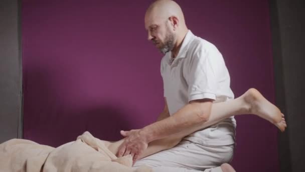 Benessere massaggio ai piedi. Primo piano dell'osteopata che fa massaggi manipolativi. Uomo mani massaggio femminile. concetto di centro benessere — Video Stock