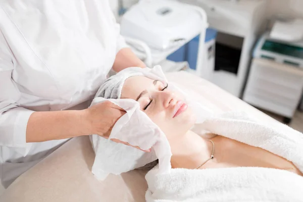 Limpe com o rosto de guardanapo estéril. Jovem mulher bonita recebendo tratamentos em salões de beleza. Espuma de limpeza facial usando . — Fotografia de Stock