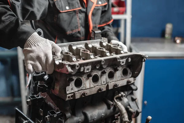 De monteur demonteert blok motor voertuig. Motor op een reparatie staan met zuiger en drijfstang van automotive technologie. Interieur van een auto reparatiewerkplaats. — Stockfoto