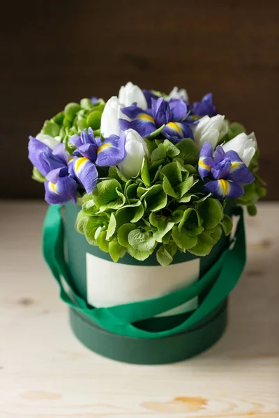 Mixed flowers . Bouquet of hydrangea, irises, tulips in a box on wooden table. copy space.