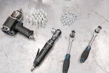 Kompresör anahtarı. Krom vida somun ve civata yukarıdan. Birçok somun ve civata vida. Vida somun ve cıvata metal gri bir arka plan üzerinde farklı boyutlarda.