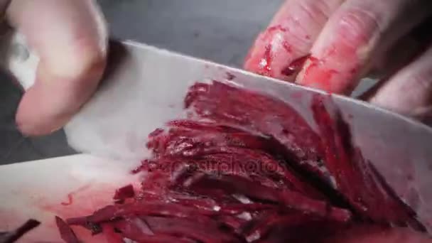 Fechar a mão com faca cortando vegetais frescos. Jovem chef cortando beterraba em uma tábua de corte branca closeup. Cozinhar em uma cozinha de restaurante — Vídeo de Stock