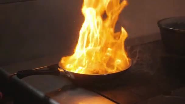 Matlagning med eld i stekpanna. kycklingbröst. Professionell kock i ett kommersiellt kök matlagning. Man steka mat i stekpanna på kokplatta i köket. slowmotion — Stockvideo
