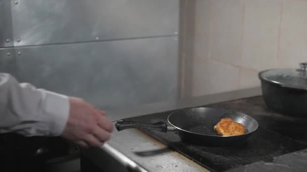 Matlagning med eld i stekpanna. kycklingbröst. Professionell kock i ett kommersiellt kök matlagning. Man steka mat i stekpanna på kokplatta i köket. slowmotion — Stockvideo